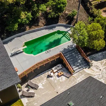 Close-up of a backyard pool, highlighting the newly installed roof by GBR Roofing.