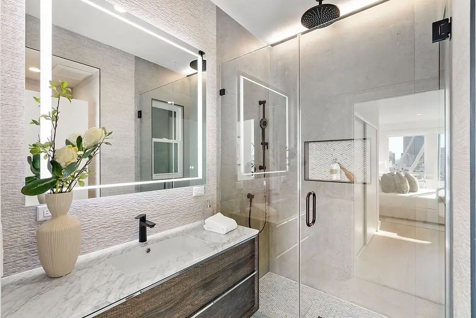 Modern bathroom remodel with glass shower, marble vanity, matte black fixtures, and illuminated mirror.