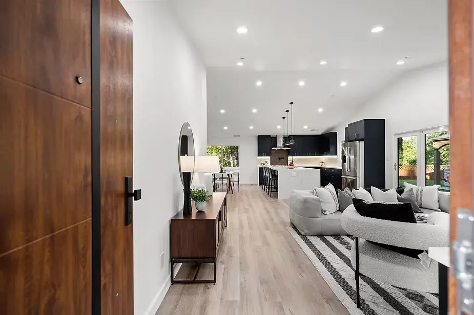 Full home renovation in Concord, CA featuring an open-concept layout with light wood flooring, black kitchen cabinetry, marble island, and stylish living area, viewed from the front door.