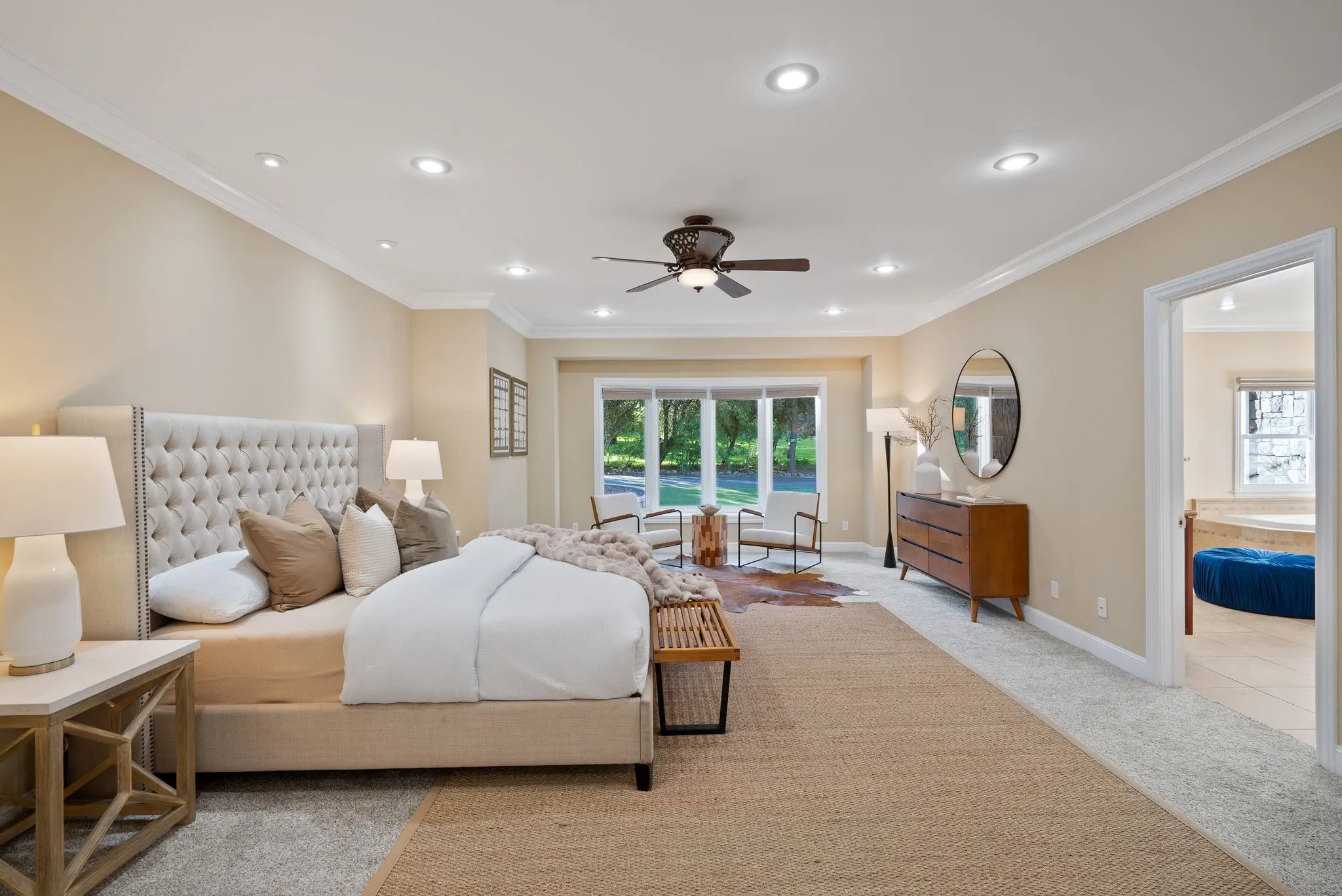 Remodeled master bedroom with seating area, carpet flooring, and natural light.