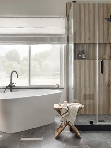 Modern bathroom with wood slat shower, black fixtures, freestanding tub, and natural wood vanity under soft daylight – Green Bay Remodeling