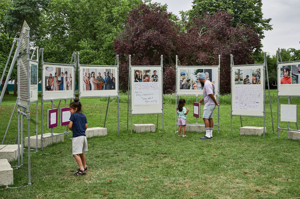 photo of children and their dad playing around a pop up exhibition in a park