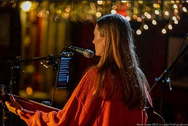 Cailin playing guitar and singing at an open mic night.