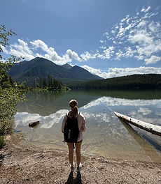 Cailin is standing at the edge of Holland Lake in Montana, looking toward some mountains.