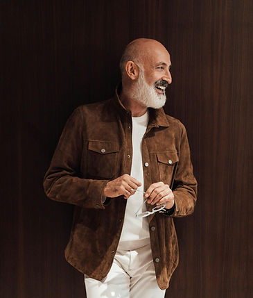Confident midlife man smiling and relaxed in a suede jacket, representing energy and self-assurance after testosterone therapy.