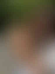 Woman holding and looking at a brown and white curly-coated puppy in natural outdoor light.