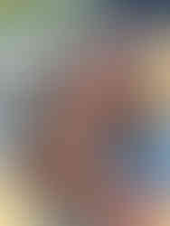 Woman holding and cuddling a small brown curly-haired puppy outdoors, smiling as she looks at the puppy.