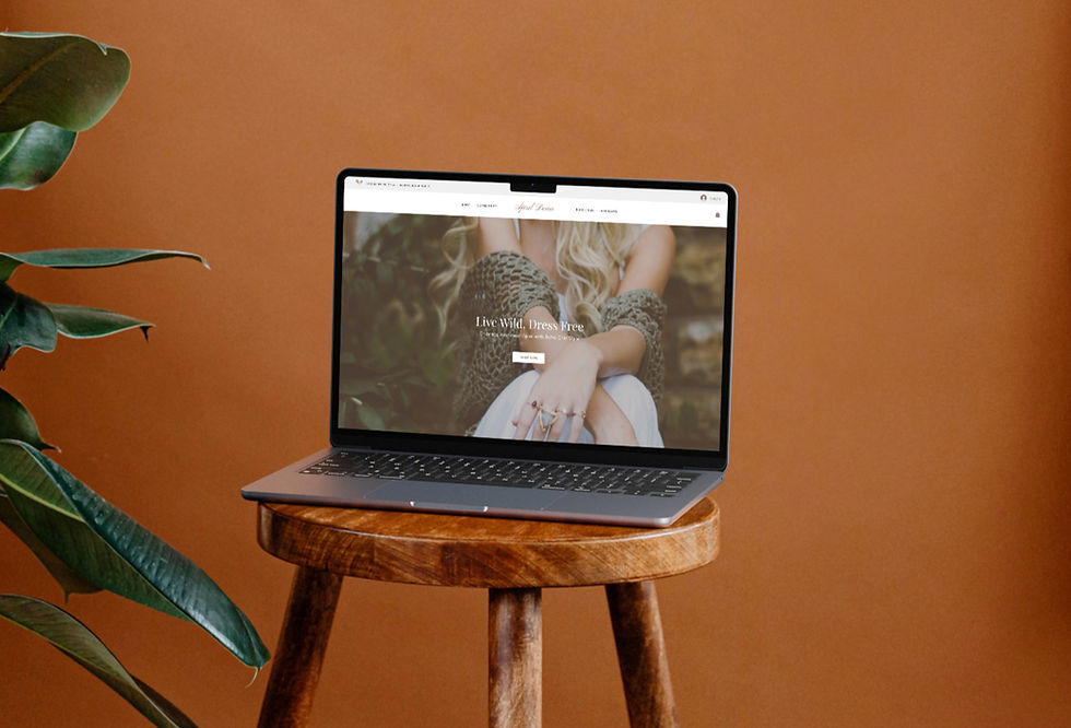 Laptop displaying website with text "Live Wild, Dress Free" on a stool. Brown background, plant leaves on the side, calm and stylish mood.
