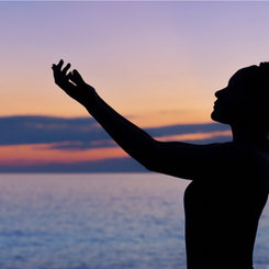 Silhouette of woman standing in front of ocean at sunset - Abiding Reiki Holistic Healing