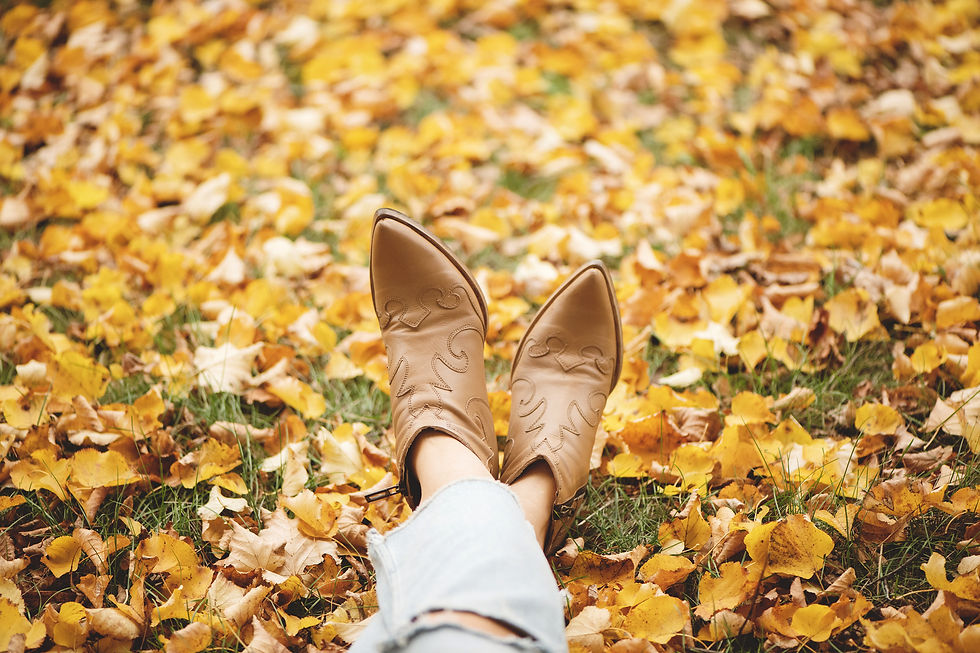 girl relaxing in fall leaves wearing cowboy boots