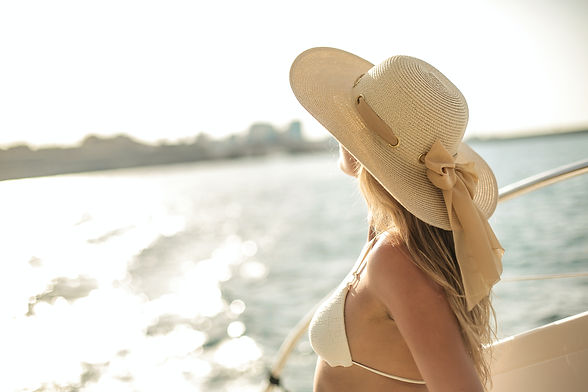 woman on boat wearing bikini and beach hat looking out into the water