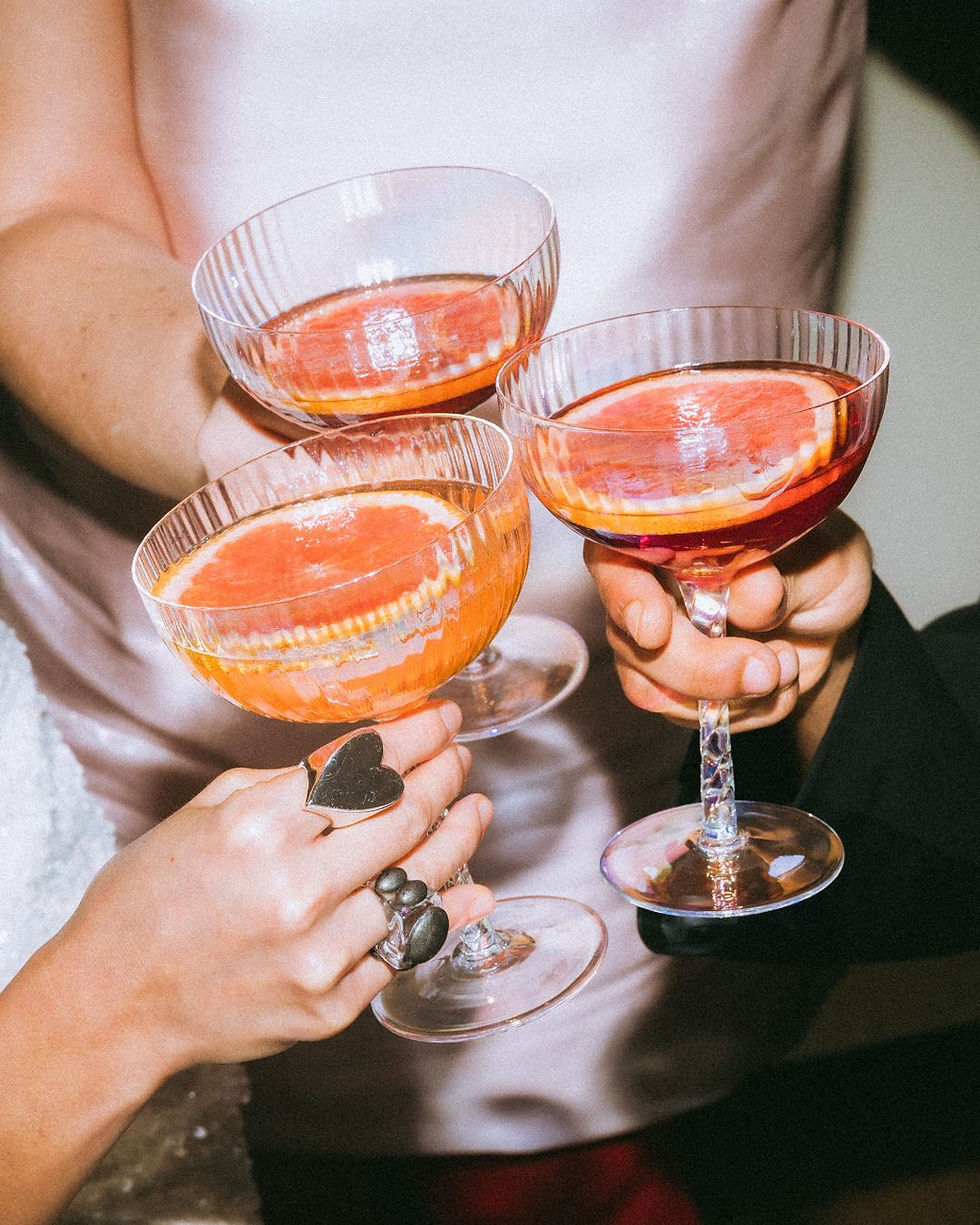 Celebratory toast with cocktails featuring grapefruit slices, Signature Sips.