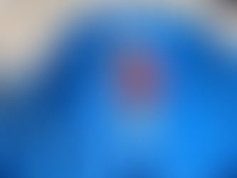 Two workers in wide-brimmed hats spray the inside of a bright blue pool. Sunny day with houses and trees in the background.