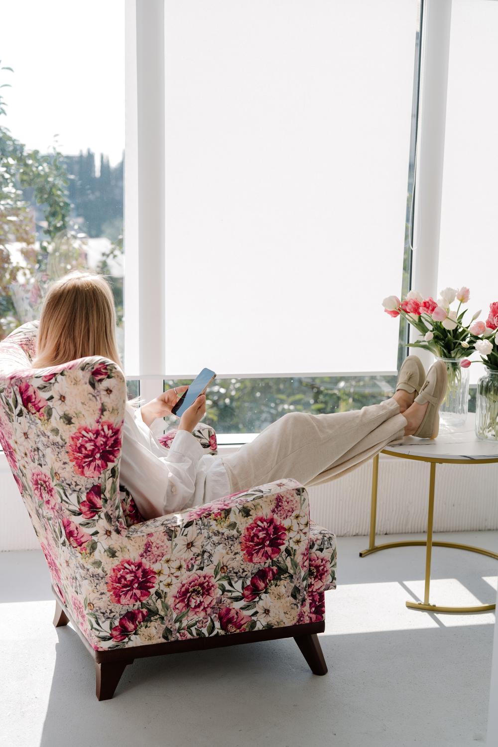 Woman working at a bright, feminine home office with soft pink decor and natural light.