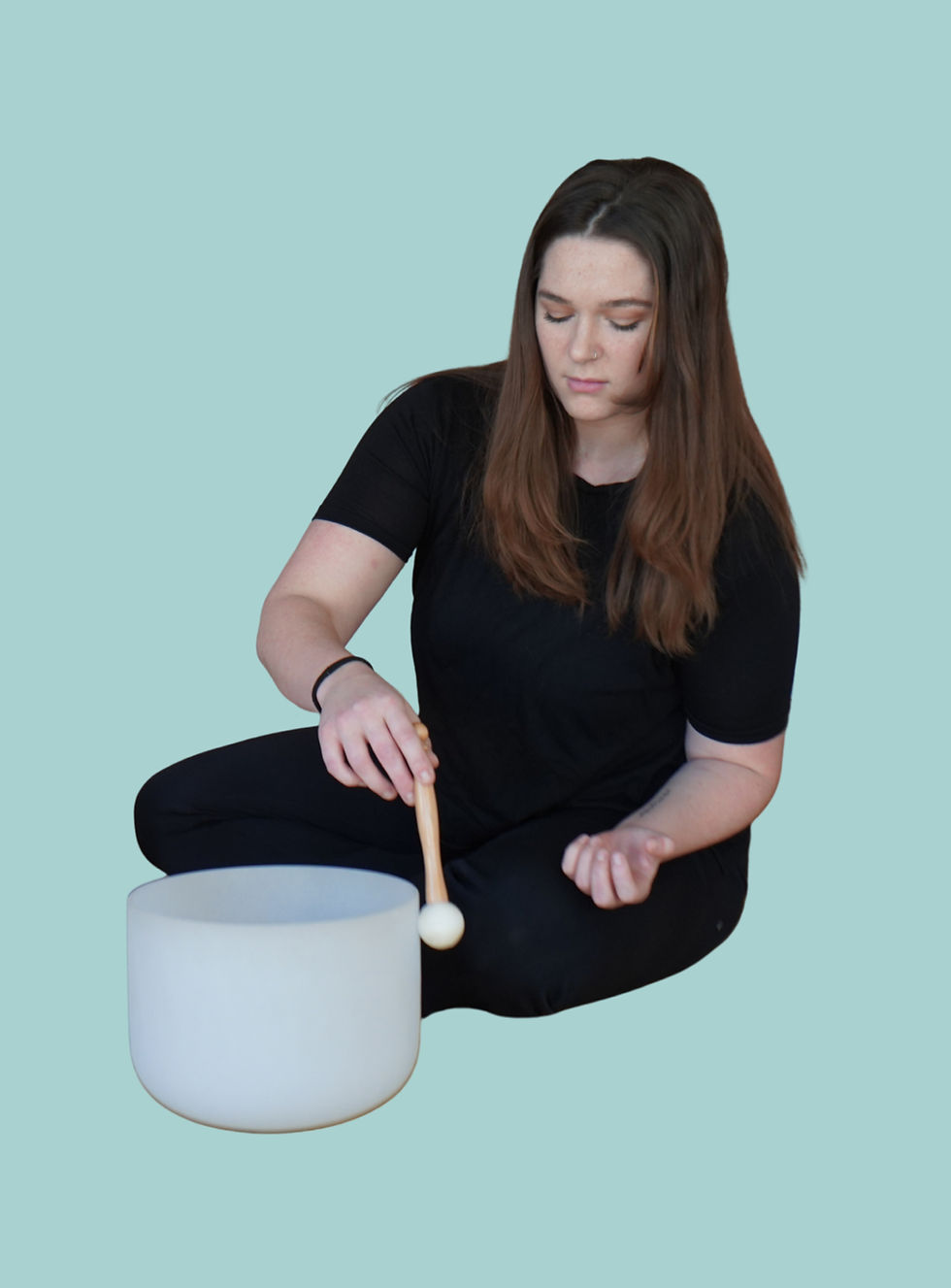 Woman sitting cross-legged playing a crystal singing bowl