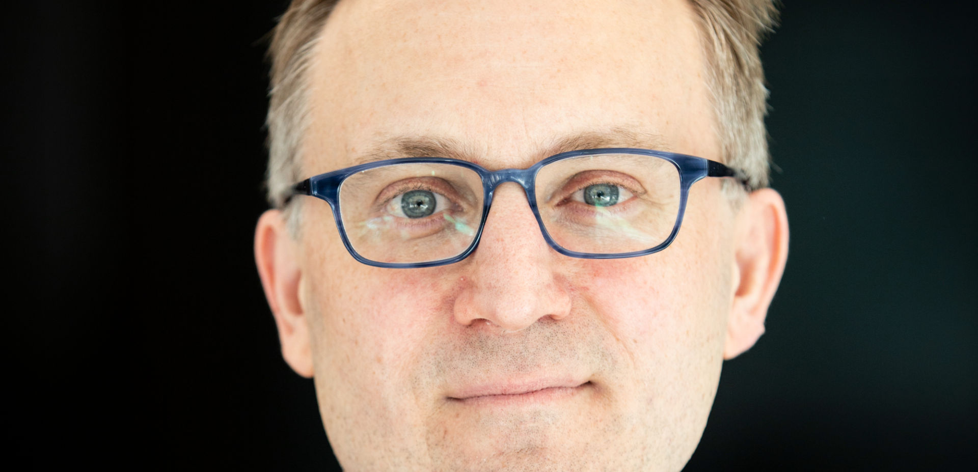 Man in blue suit, glasses, and patterned tie