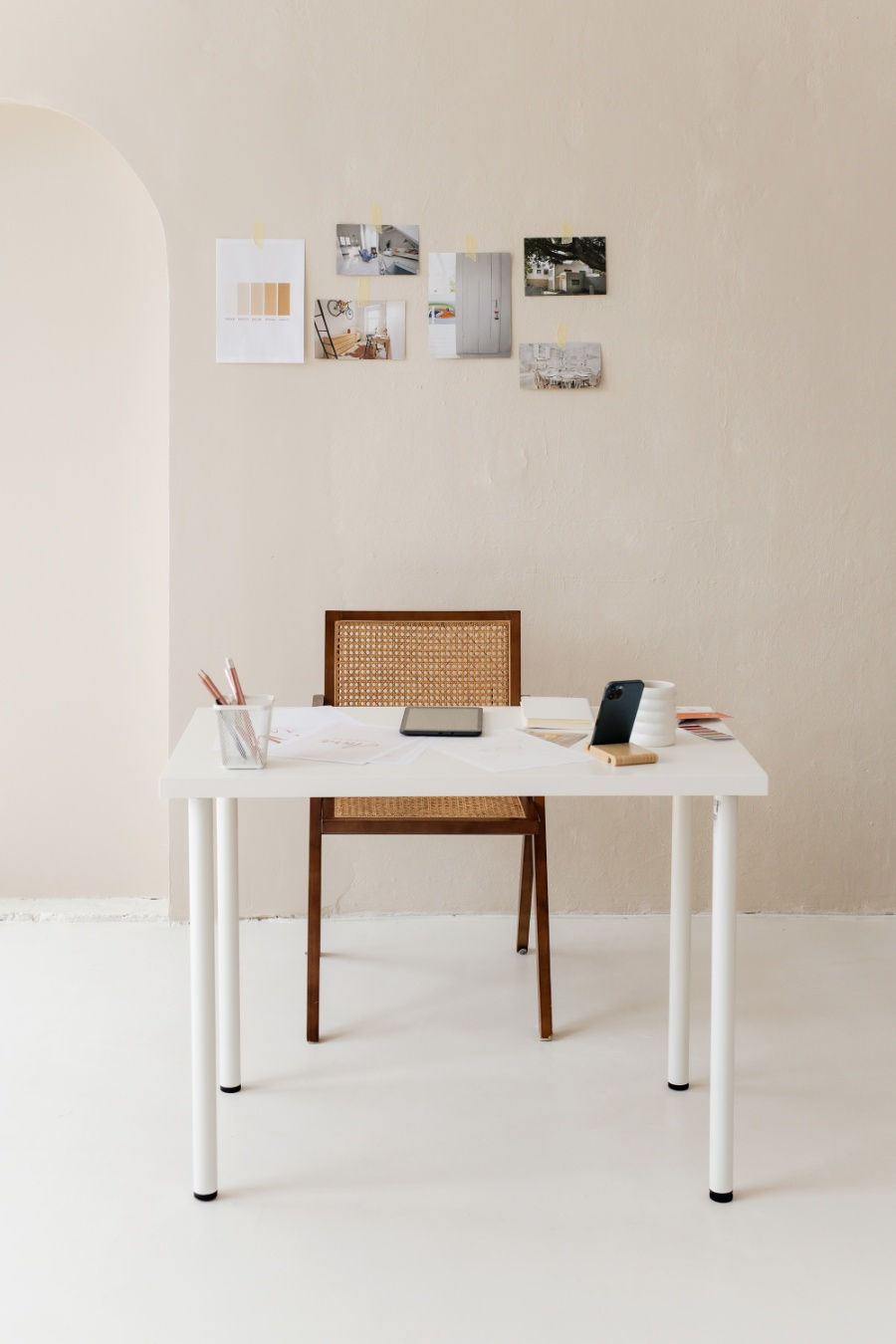 Minimalist home office with wooden desk, chair, and neutral decor in a bright room.