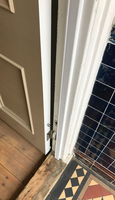 London joiner routing a hidden groove into a historic Victorian front door for invisible heritage draught proofing.