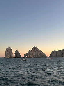 Golden sunset illuminating iconic rock arch formations rising from Pacific Ocean waters in Los Cabos, Mexico