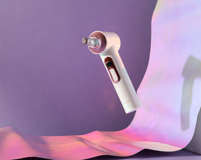 White personal microdermabrasion device floating on purple background with holographic accent.