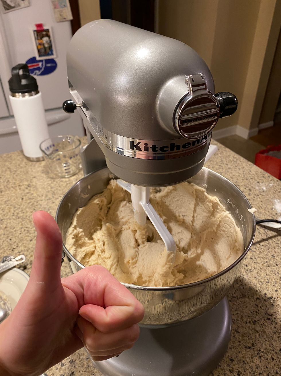 Katherine holding up another thumbs up in front of her finished dough in the KitchenAid mixer.