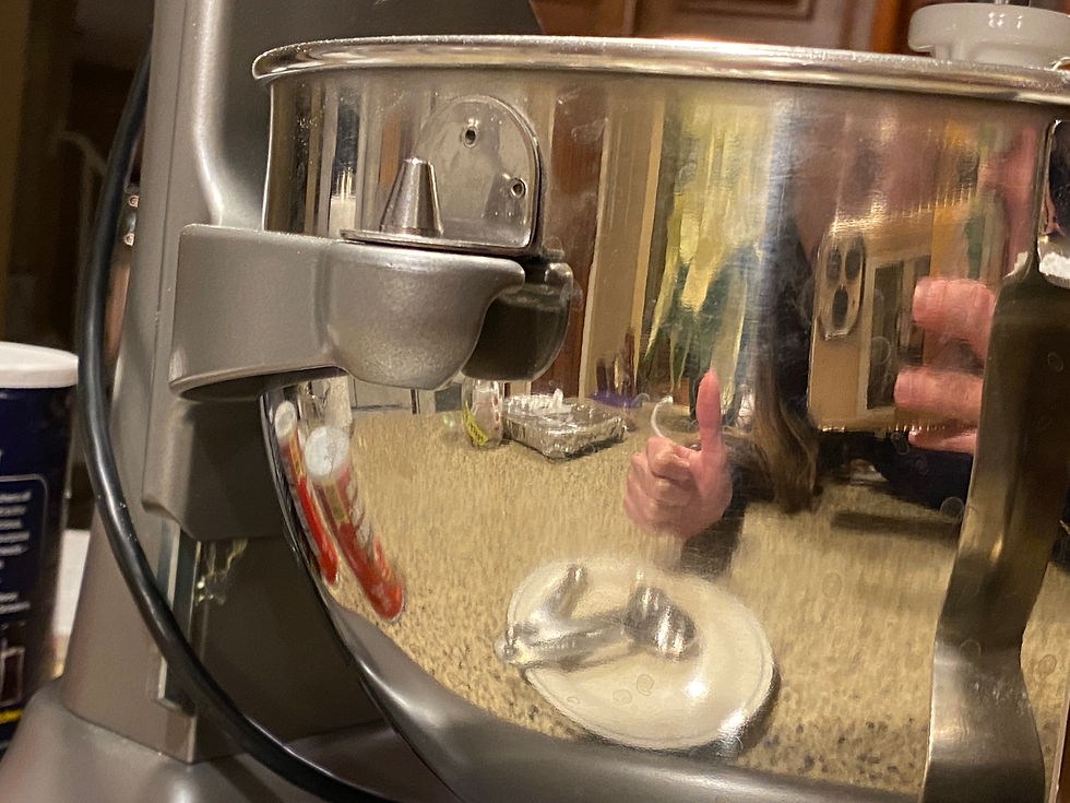 Katherine holding up a thumbs up in the reflection of the KitchenAid mixer.