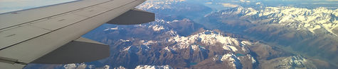 Plane wing over snowy mountains