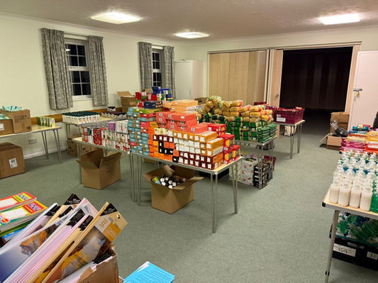 Tables stacked with donated food and supplies for Leave No One Behind.