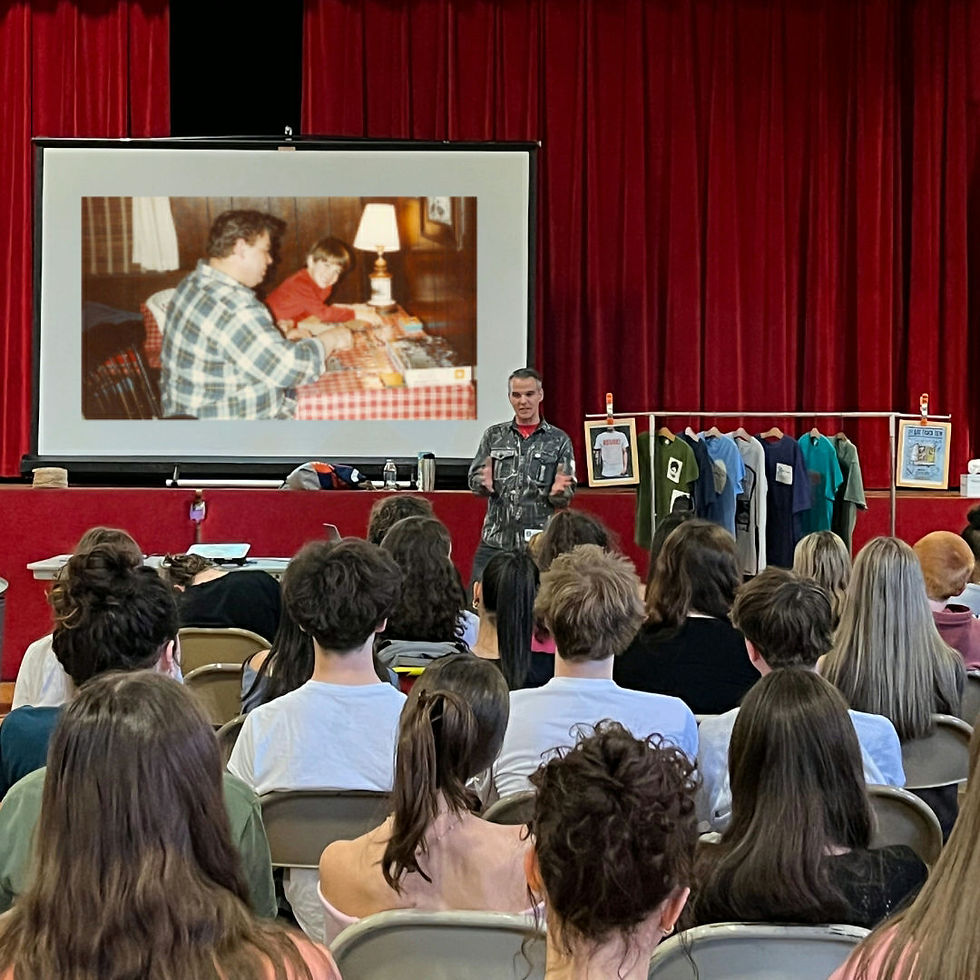 A man talks to a group of students in front of a film screen.