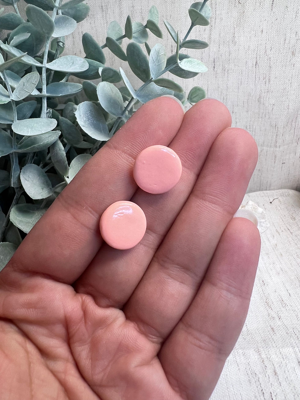 Deux boucles d'oreilles rondes roses dans une main