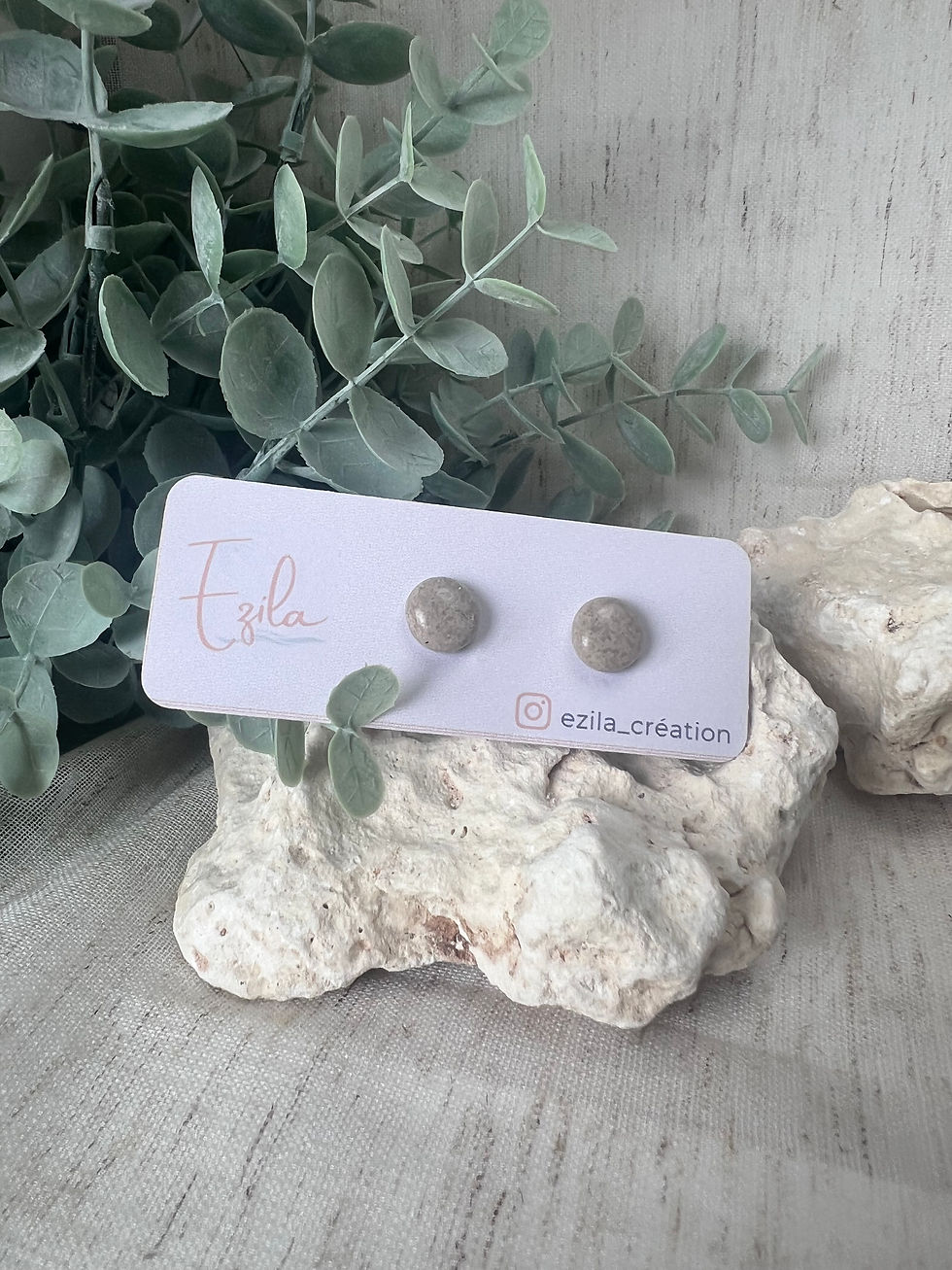 Boucles d'oreilles clous rondes sur carte, posées sur roche.