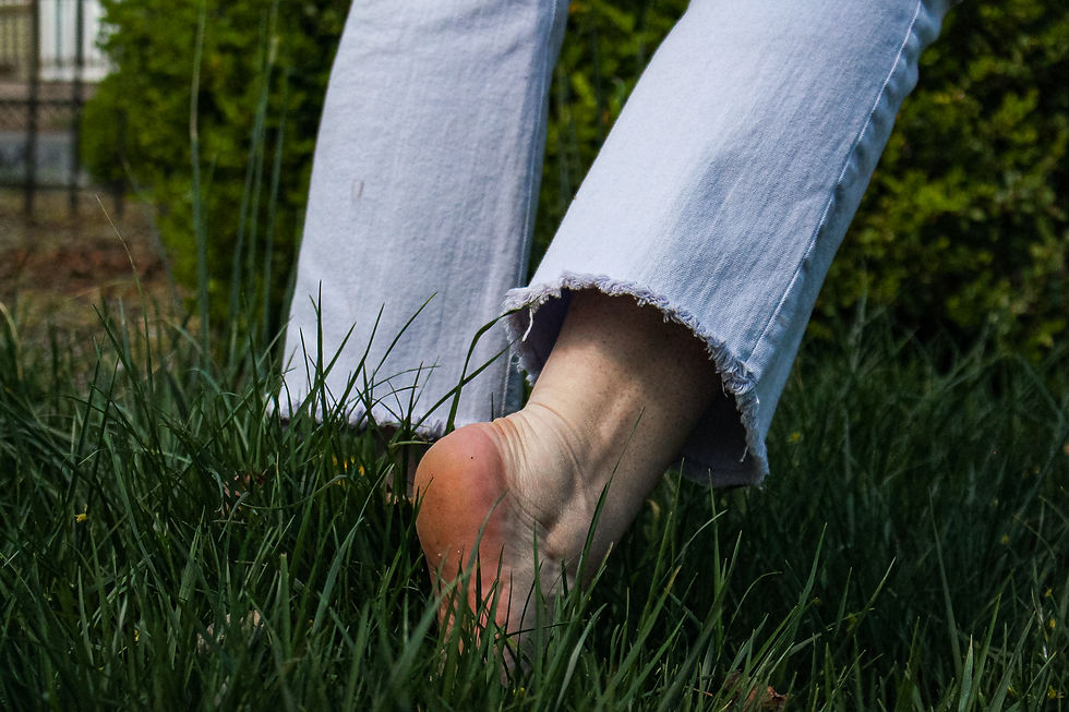 close up of woman in frayed jeans from knees-down walking in dark green grass