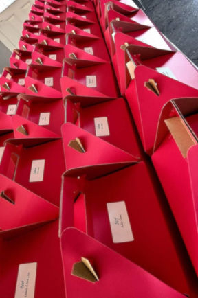 Rows of red triangular boxes with visible white labels placed on a black surface, creating a neat and organized pattern.