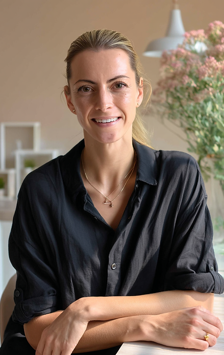 Eine junge Frau Mitte dreißig, Rebecca Michhke, Gründerin von HEALTHComm Marketing & Kommunikation aus Düsseldorf, schaut freundlich lächelnd in die Kamera, die Arme entspannt vor sich auf dem Tisch abgelegt, sie trägt eine schwarze, legere Bluse