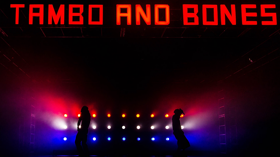 Tambo & Bones - two actors are silhouetted against a wall of red, white, and blue lights