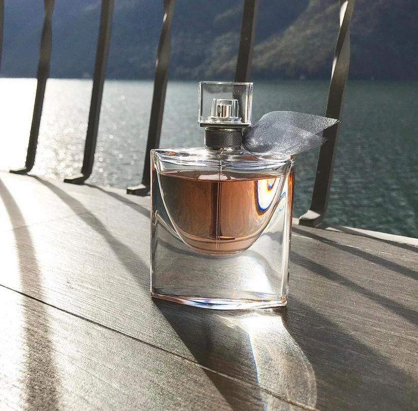 Miniatura: Foto do frasco do perfume La vie Est Belle de Lancôme em cima de uma ponte ao fundo da imagem um lago
