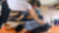 MIchal Ironi supports a yoga studend during a yoga class
