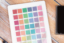 Tablet displaying a color chart with various shades and names on a wooden table. Nearby is a phone and "Bonny's Styling" text.