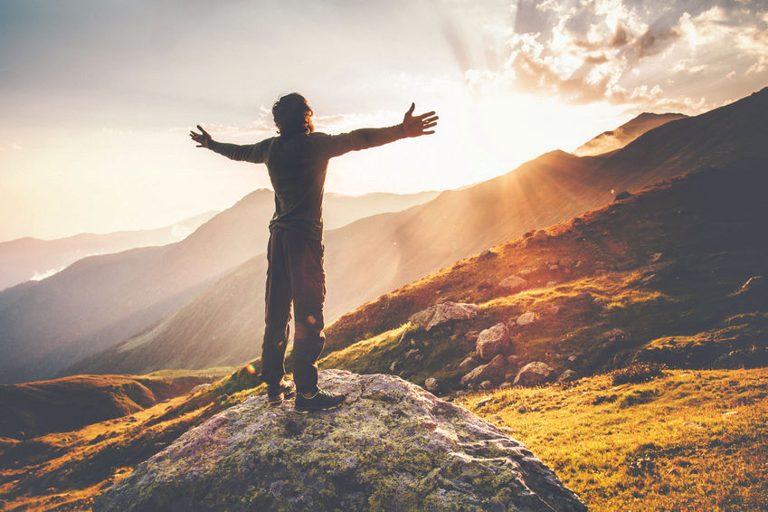 Man standing on mountain arms open with vibrant health
