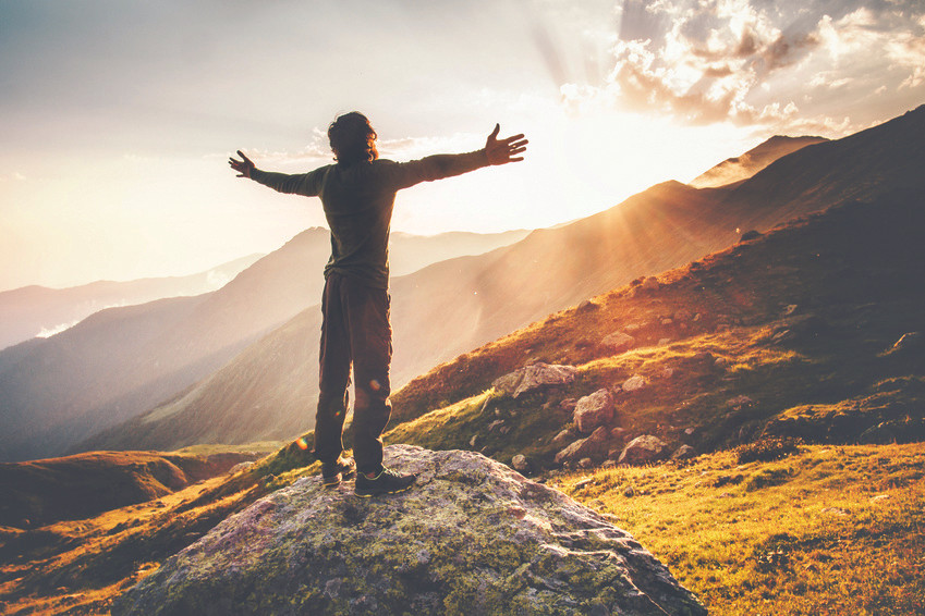 Man standing on mountain arms open with vibrant health
