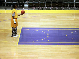 Kobe Bryant standing alone in an empty basketball arena during a late night training session, representing discipline and obsession behind greatness