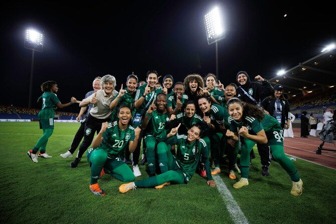 Saudi women’s national football players celebrating together after a match under stadium lights