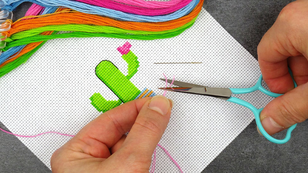 Cross stitch in progress with small embroidery scissors cutting the tatty ends of embroidery thread