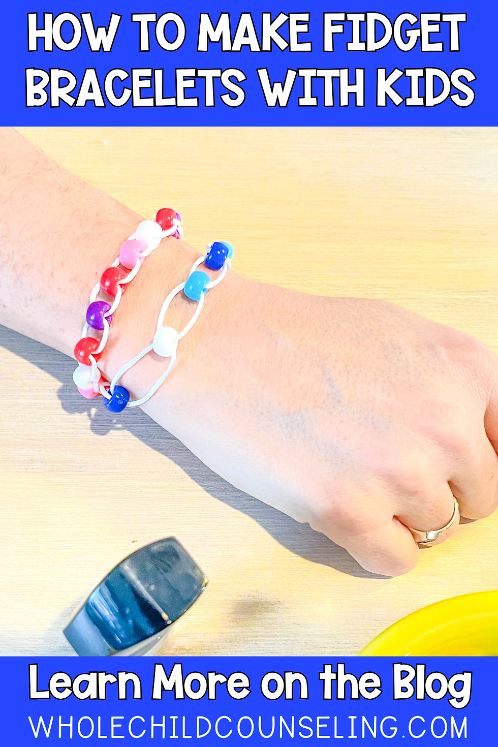 Hand wearing colorful fidget bracelets on a wooden surface. Text: "How to Make Fidget Bracelets with Kids" and "Learn More on the Blog."