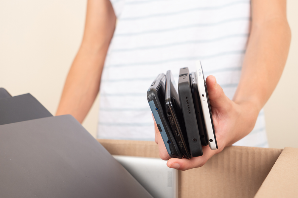 Woman holding a handful of cell phones and boxing them up to donate to the 911 Cell Phone Bank