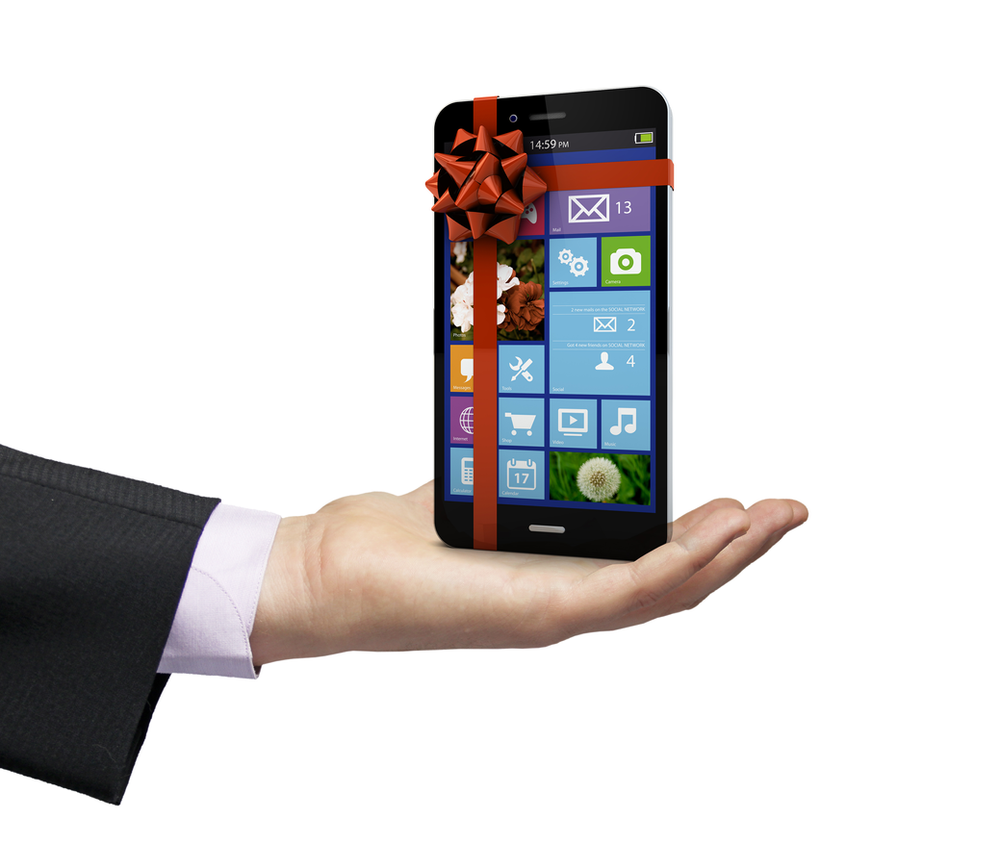 hand of a boss gifting a cell phone to an employee. The phone has red ribbon and bow around it.