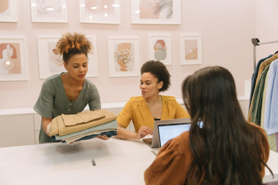 Three women collaborating on their business with clothing and computers