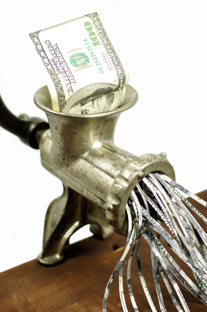 Vintage meat grinder shredding a $100 bill