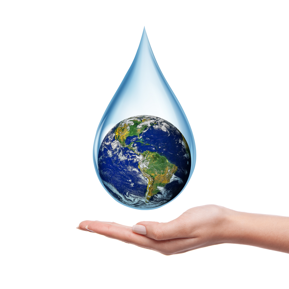 green energy concept of a water drop with the earth inside of it, being held in the palm of a hand