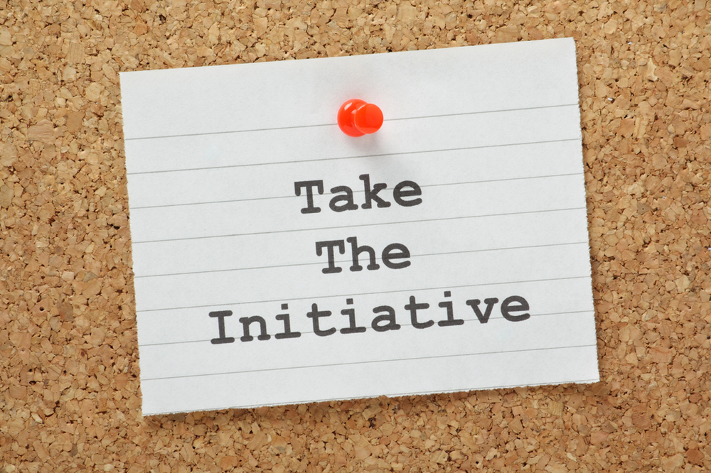 Corkboard with an index card pinned on it that says "Take the Initiative"